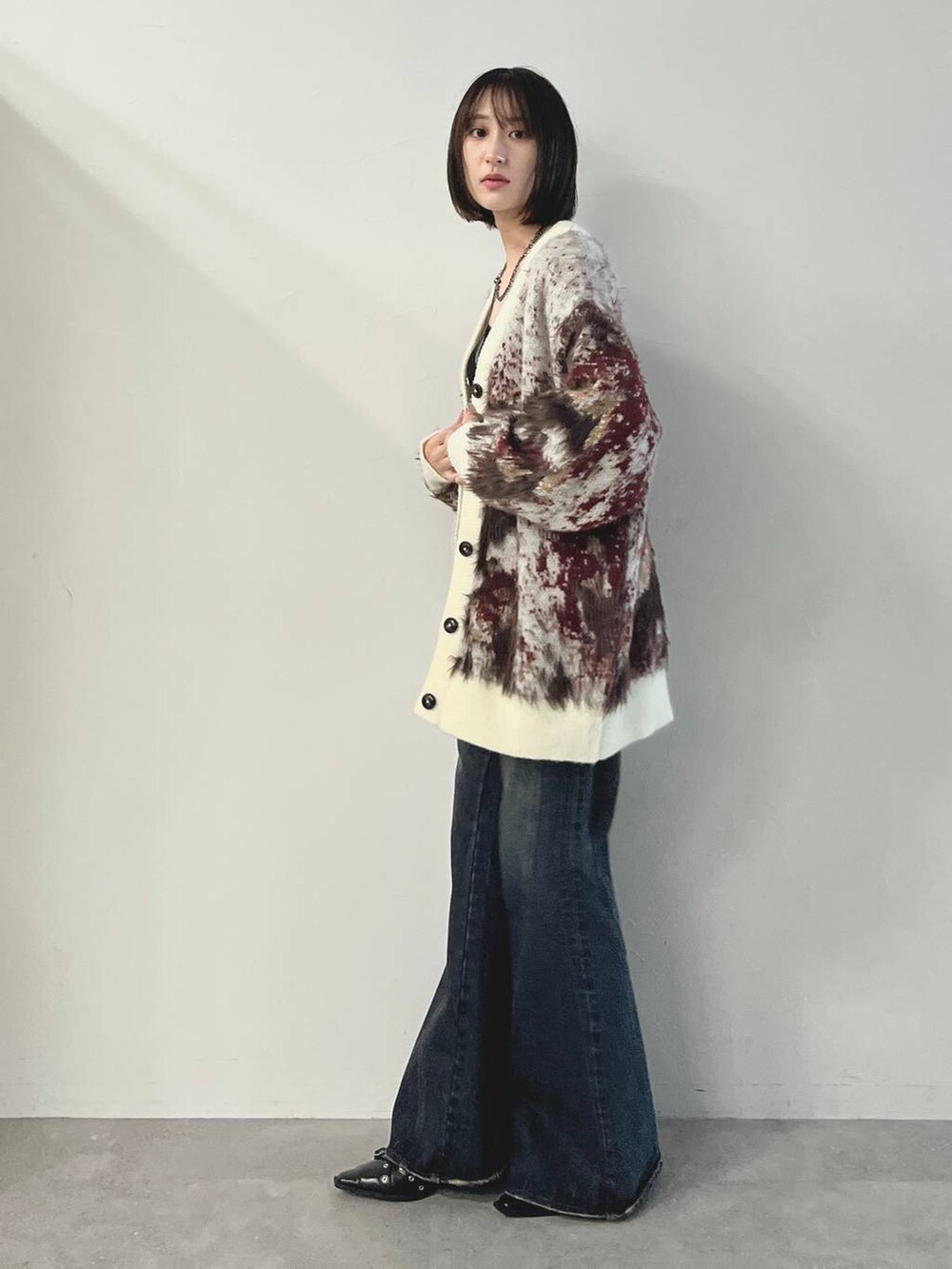 ブルー系のデニムパンツ、ブラック系のパンプス、ホワイト系のカーディガン/ボレロを着用したレディースの秋コーディネートの5枚目の写真