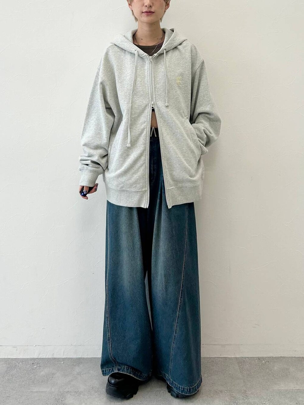 ブルー系のデニムパンツ、ブラック系のブーツ、グレー系のパーカーを着用したレディースの秋コーディネートの3枚目の写真