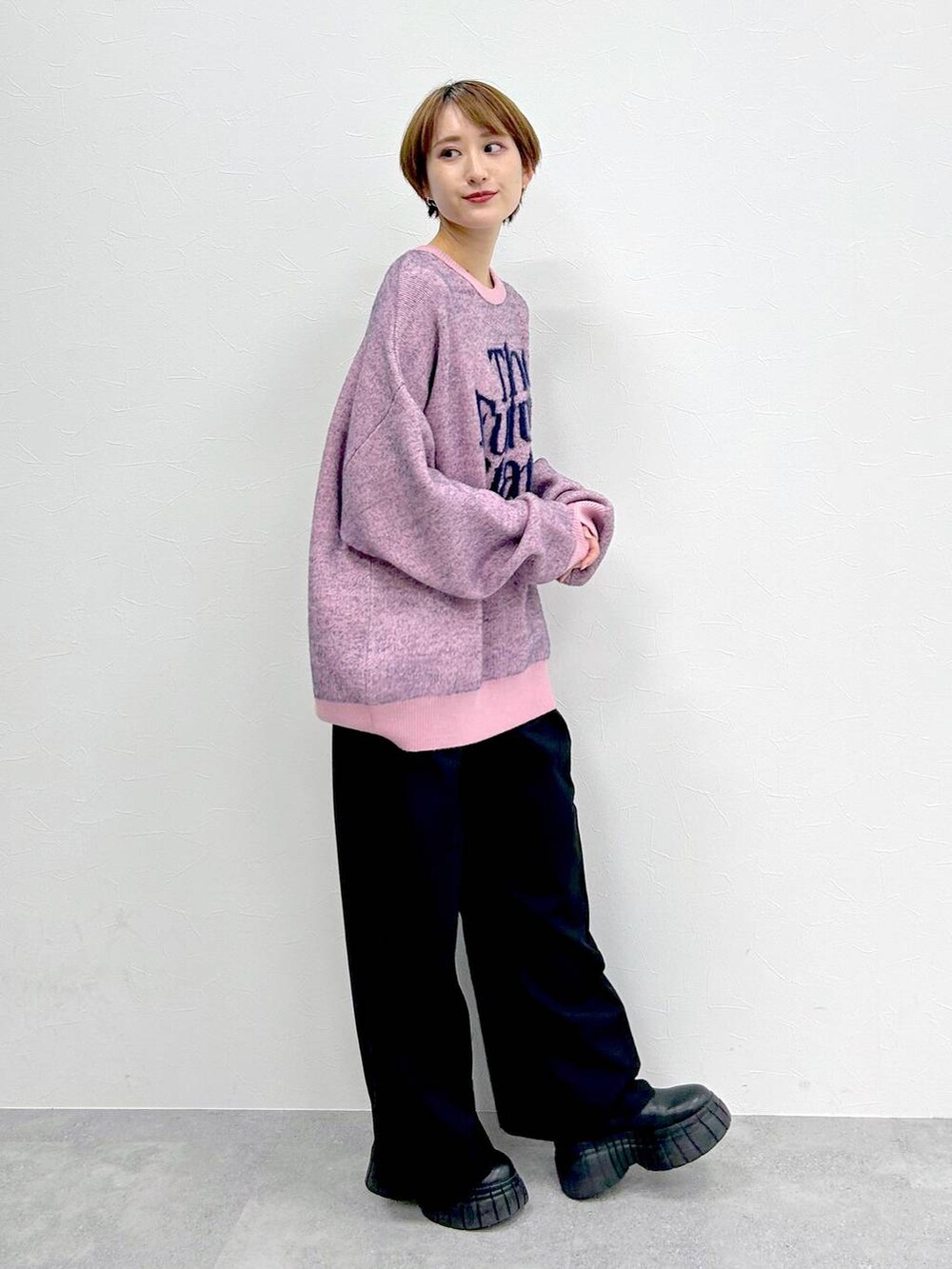 ピンク系のニット/セーター、ブラック系のブーツ、ブラック系のスラックスを着用したレディースの冬コーディネートの5枚目の写真