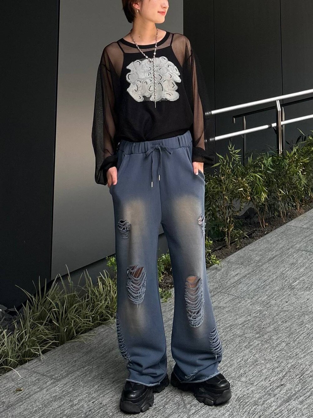 ブラック系のスニーカー、ブルー系のスウェットパンツ、ブラック系のニット/セーターを着用したレディースの夏コーディネートの2枚目の写真