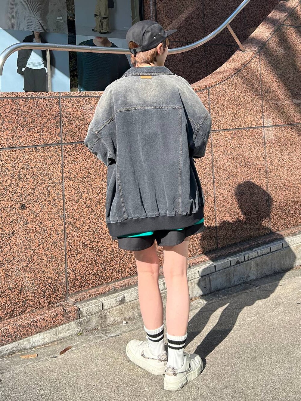 ブラック系のデニムジャケット、グリーン系のTシャツ/カットソー、ブラック系のキャップを着用したレディースの春コーディネートの4枚目の写真