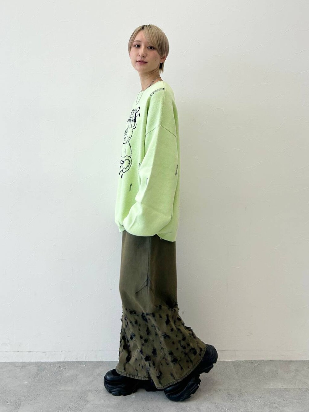 ブラック系のデニムパンツ、ブラック系のブーツ、グリーン系のニット/セーターを着用したレディースの秋コーディネートの3枚目の写真