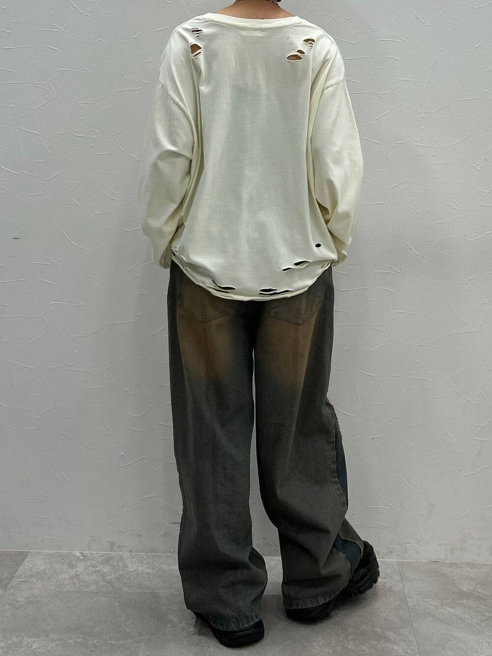 ブラック系のスニーカー、ホワイト系のTシャツ/カットソー、ブルー系のデニムパンツを着用したレディースの秋コーディネートの7枚目の写真