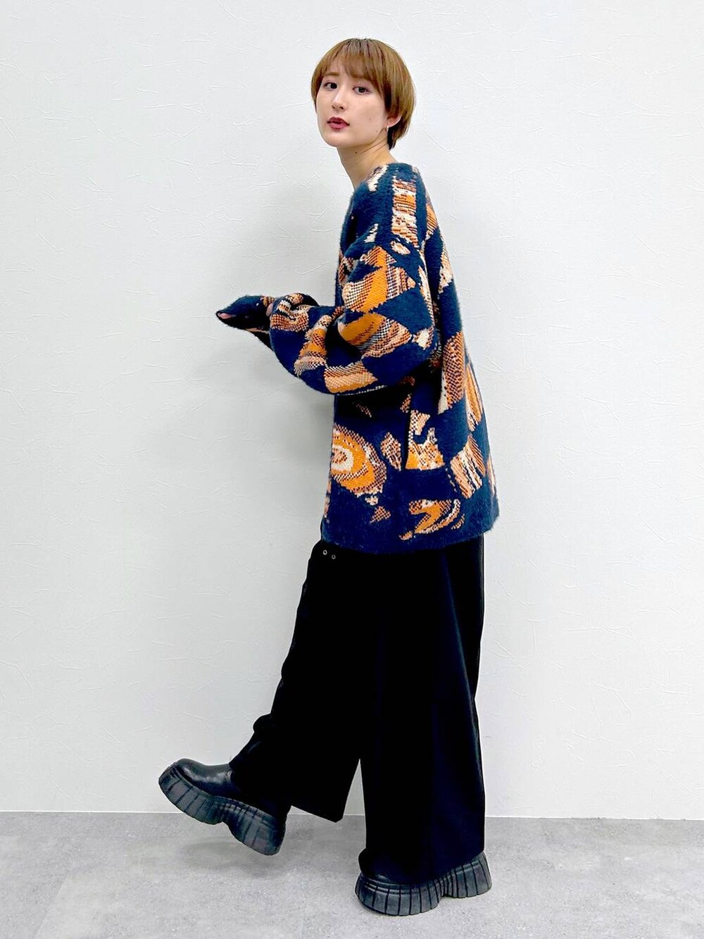 ブルー系のニット/セーター、ブラック系のブーツ、ブラック系のスラックスを着用したレディースの冬コーディネートの3枚目の写真