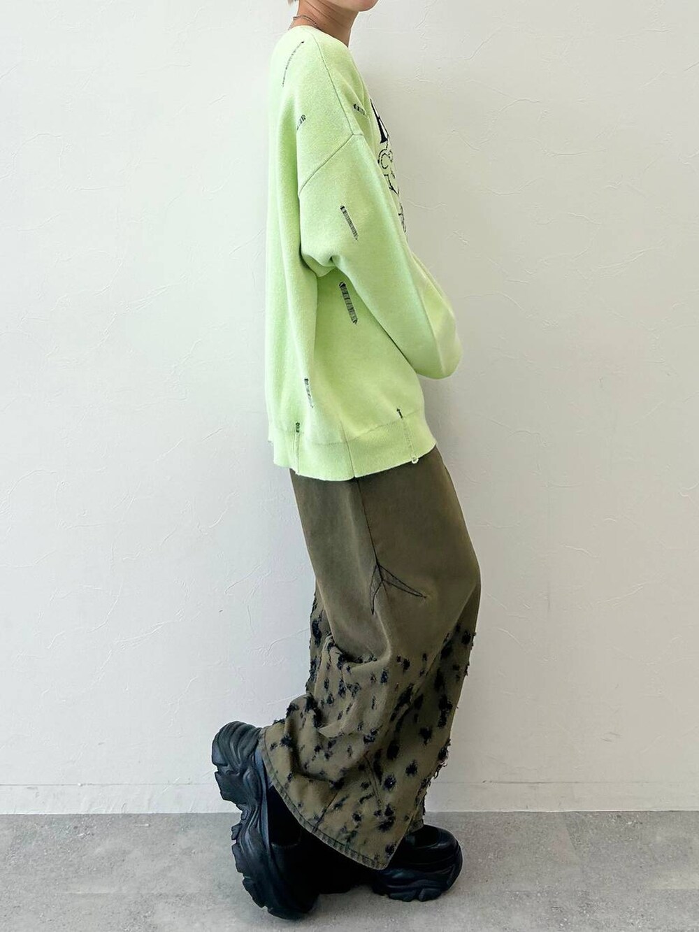 ブラック系のデニムパンツ、ブラック系のブーツ、グリーン系のニット/セーターを着用したレディースの秋コーディネートの6枚目の写真