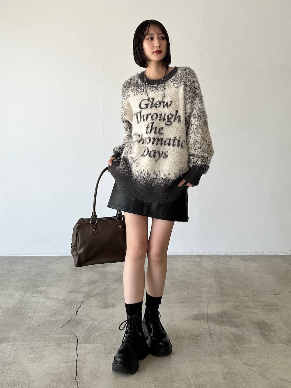 ブラック系のブーツ、ブラウン系のボストンバッグ、グレー系のニット/セーターを着用したレディースの秋コーディネートの2枚目の写真