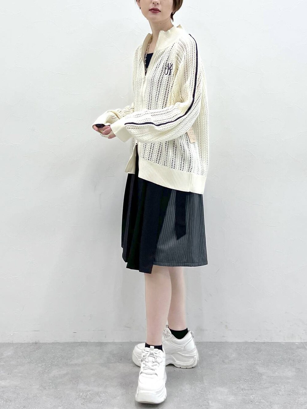 ブラック系のスラックス、ホワイト系のカーディガン/ボレロ、シルバー系のネックレスを着用したレディースの冬コーディネートの4枚目の写真