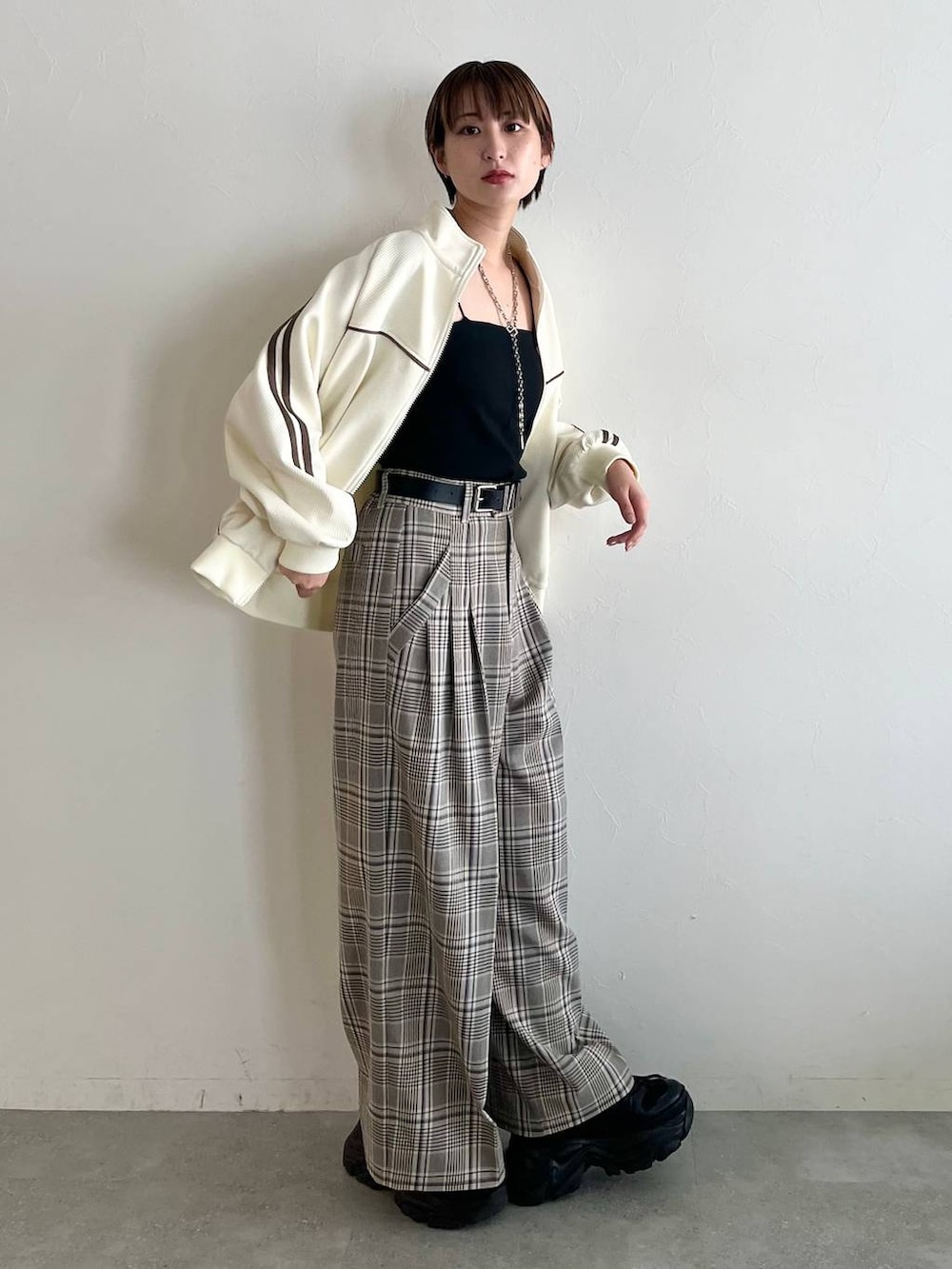 ブラック系のスニーカー、ベージュ系のスラックス、ホワイト系のジャージを着用したレディースの秋コーディネートの2枚目の写真