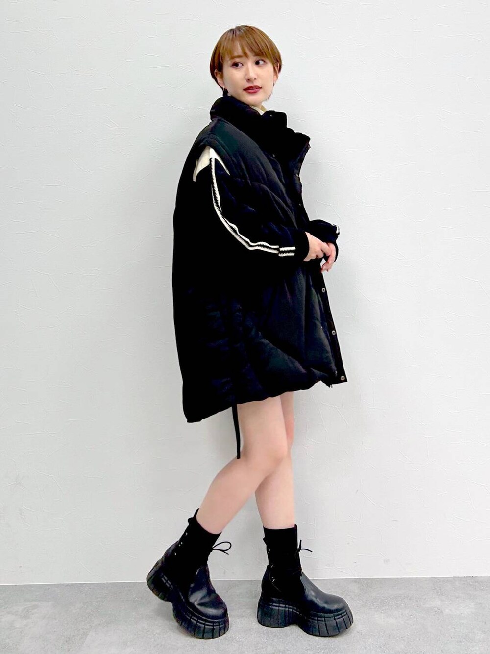 ブラック系のブルゾン、ブラック系のブーツ、ブラック系のスカートを着用したレディースの冬コーディネートの3枚目の写真