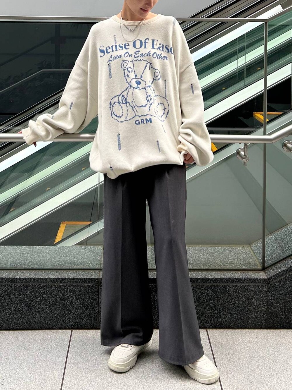 グレー系のスラックス、ホワイト系のニット/セーターを着用したレディースの冬コーディネートの2枚目の写真