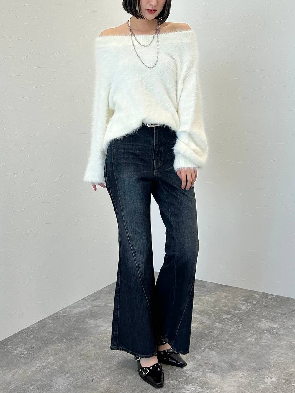 ブルー系のデニムパンツ、ブラック系のパンプス、ホワイト系のニット/セーターを着用したレディースの秋コーディネートの3枚目の写真