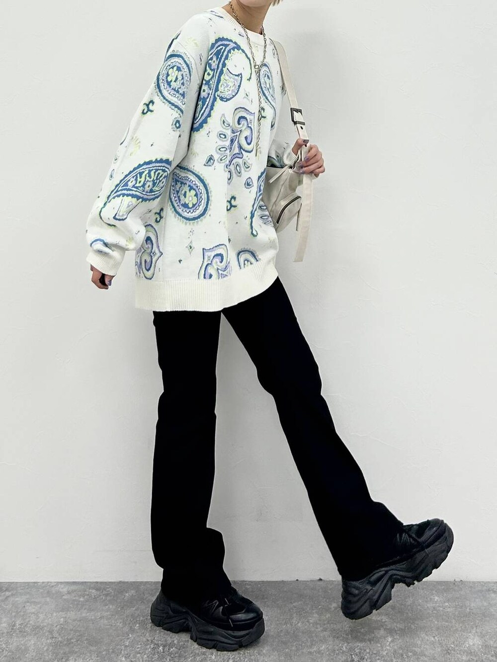 ブラック系のスニーカー、ホワイト系のショルダーバッグ、ブラック系のデニムパンツを着用したレディースの冬コーディネートの6枚目の写真