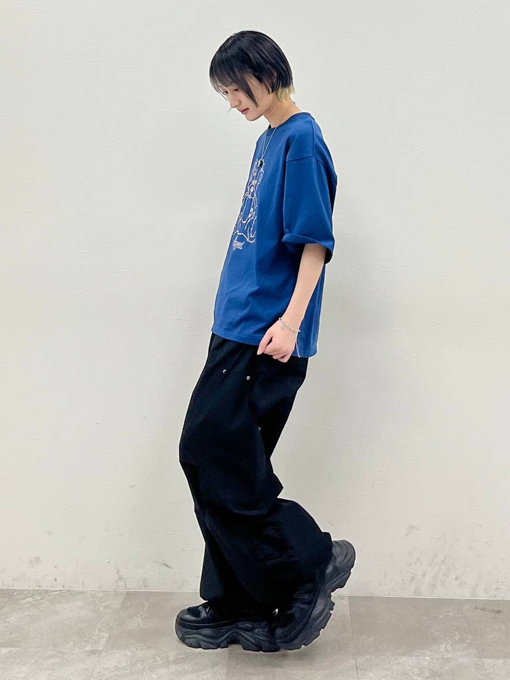 ブラック系のスニーカー、ブルー系のTシャツ/カットソー、ブラック系のカーゴパンツを着用したレディースの春コーディネートの3枚目の写真