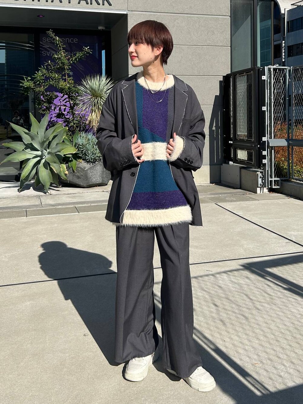グレー系のスラックス、グレー系のテーラードジャケット、ブルー系のニット/セーターを着用したレディースの冬コーディネートの2枚目の写真