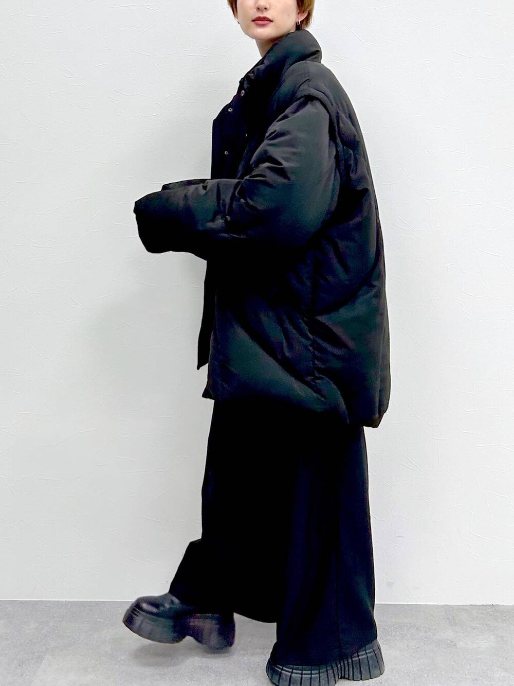 ブラック系のブルゾン、レッド系のニット/セーター、ブラック系のスラックスを着用したレディースの冬コーディネートの4枚目の写真