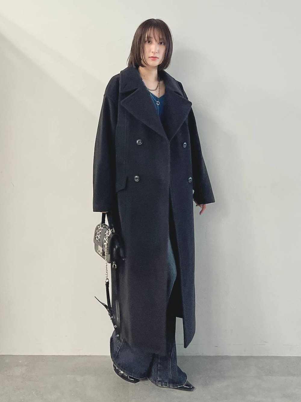 ブルー系のデニムパンツ、ブラック系のパンプス、ブラック系のチェスターコートを着用したレディースの秋コーディネートの2枚目の写真