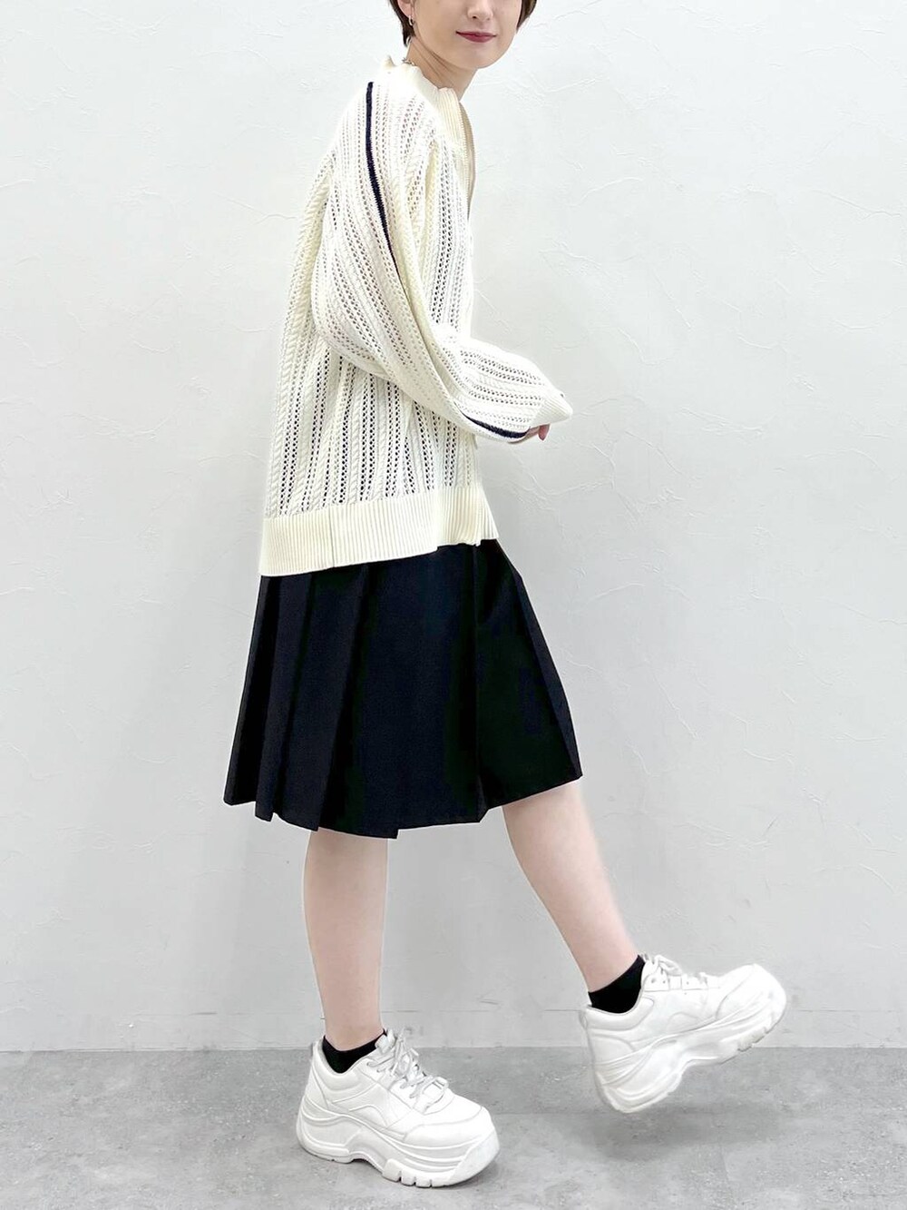 ブラック系のスラックス、ホワイト系のカーディガン/ボレロ、シルバー系のネックレスを着用したレディースの冬コーディネートの6枚目の写真