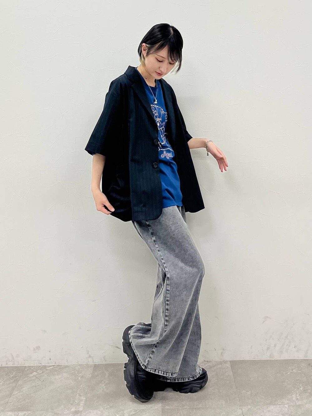 ブラック系のスニーカー、ブルー系のTシャツ/カットソー、ブラック系のデニムパンツを着用したレディースの春コーディネートの5枚目の写真