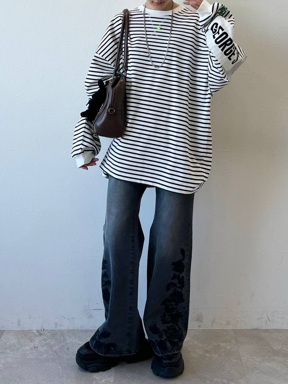 ブラック系のスニーカー、ブラウン系のボストンバッグ、ブラック系のデニムパンツを着用したレディースの春コーディネートの2枚目の写真