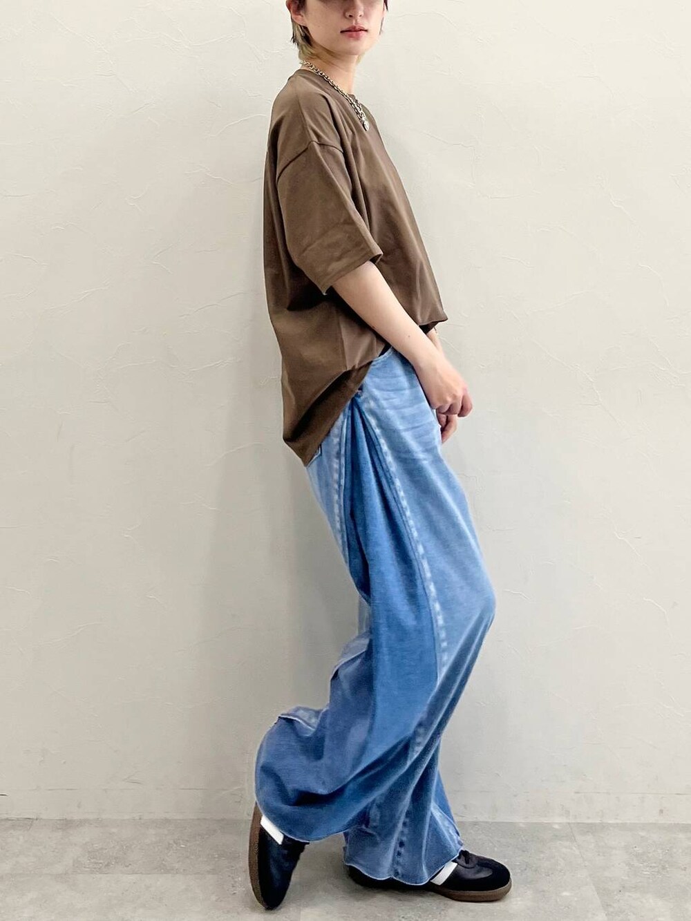 ブルー系のデニムパンツ、ブラック系のスニーカー、ブラウン系のTシャツ/カットソーを着用したレディースの春コーディネートの4枚目の写真