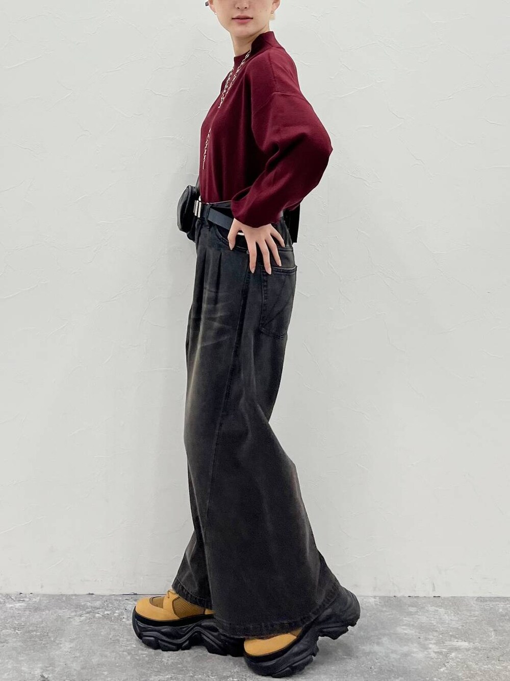 ブラック系のデニムパンツ、ブラウン系のブーツ、レッド系のニット/セーターを着用したレディースの秋コーディネートの5枚目の写真