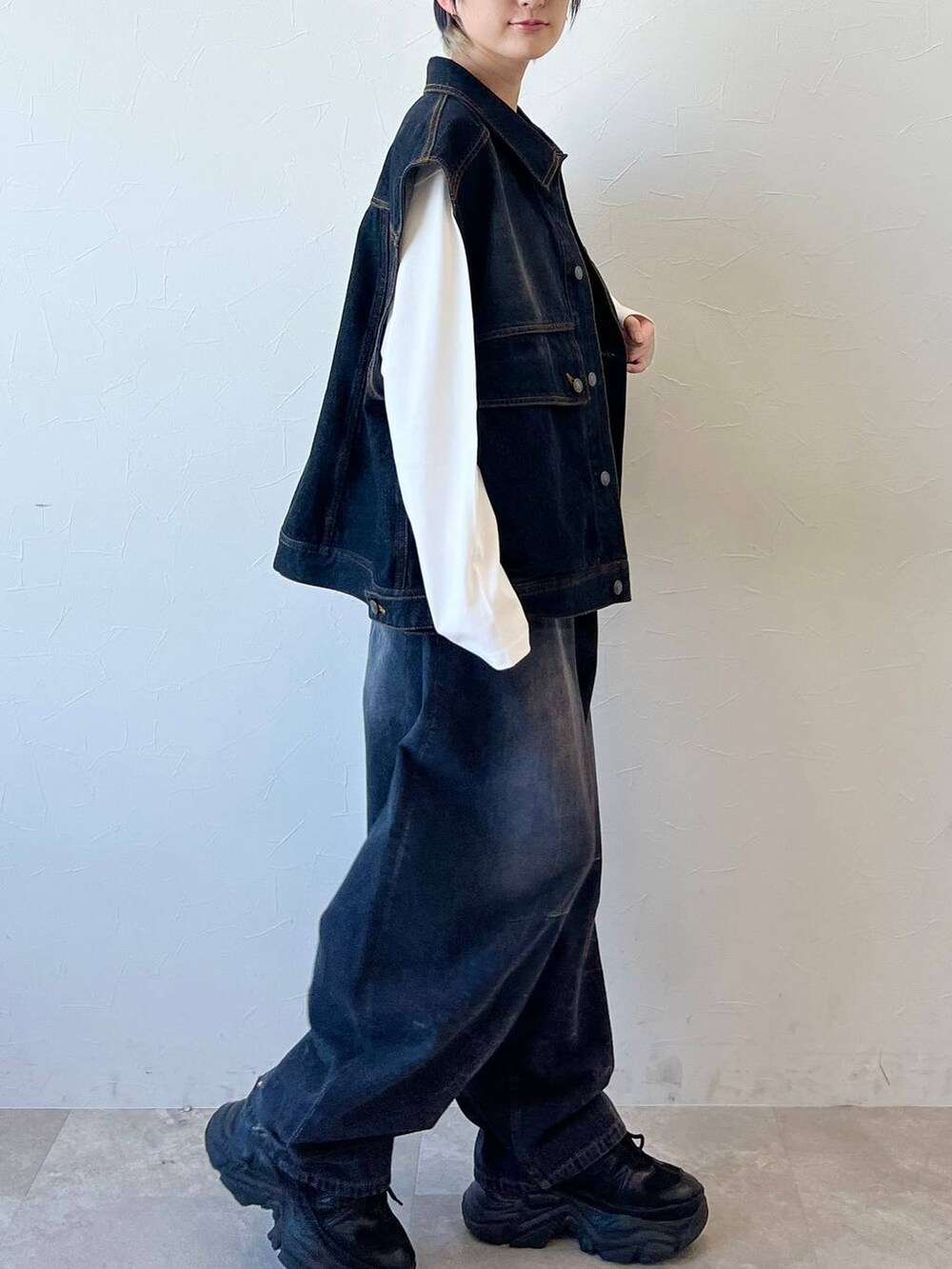 ブラック系のスニーカー、ブラック系のデニムパンツ、ブラウン系のボストンバッグを着用したレディースの春コーディネートの5枚目の写真