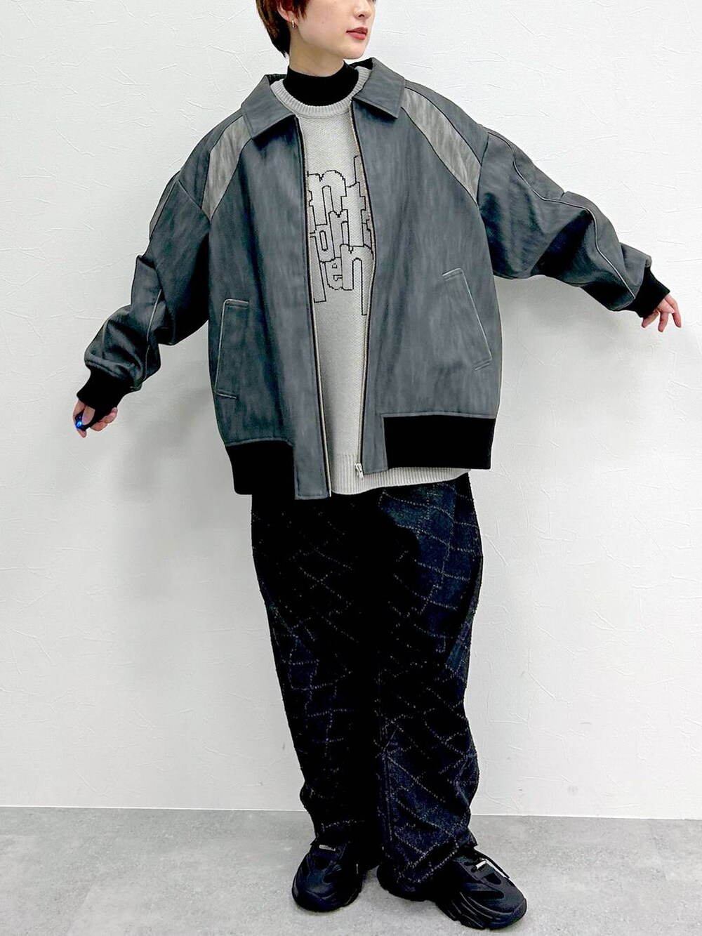 グレー系のブルゾン、ブラック系のデニムパンツ、グレー系のニット/セーターを着用したレディースの春コーディネートの2枚目の写真