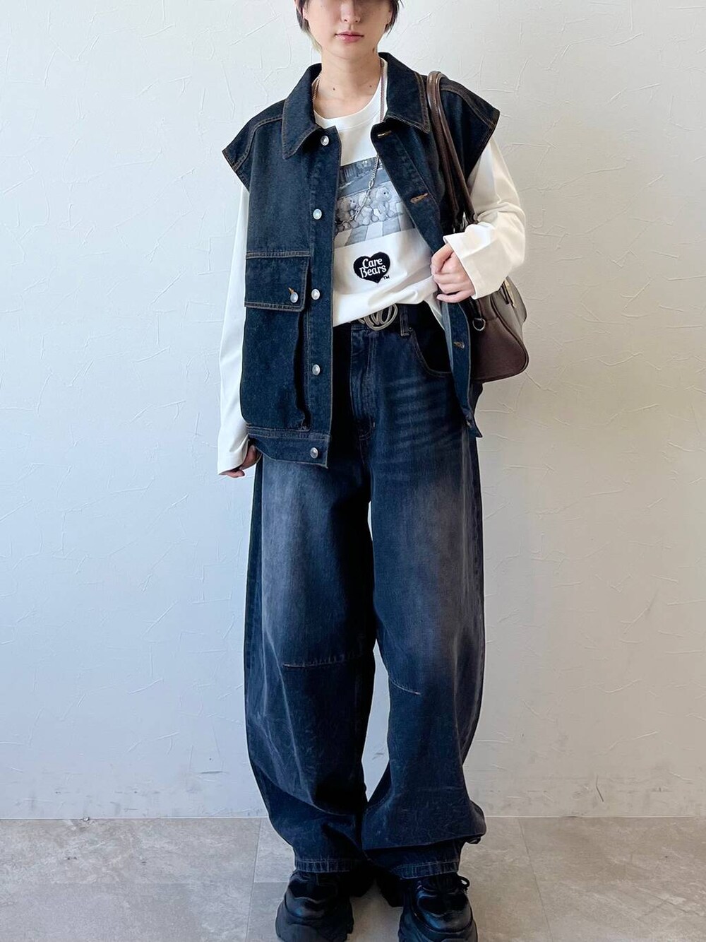 ブラック系のスニーカー、ブラック系のデニムパンツ、ブラウン系のボストンバッグを着用したレディースの春コーディネートの3枚目の写真