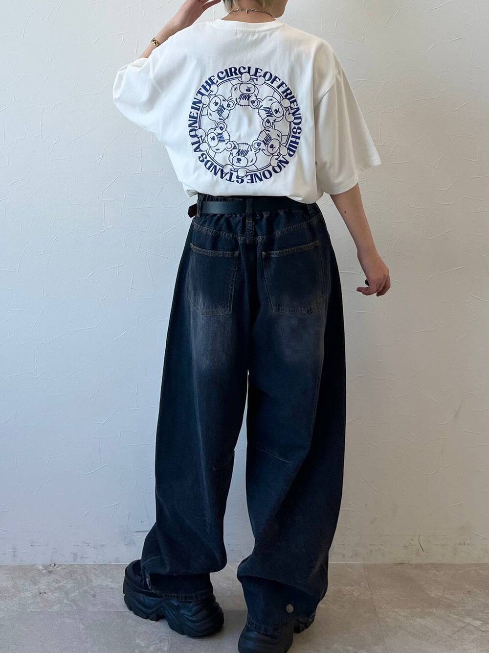 ブラック系のスニーカー、ブラック系のデニムパンツ、ホワイト系のTシャツ/カットソーを着用したレディースの春コーディネートの2枚目の写真