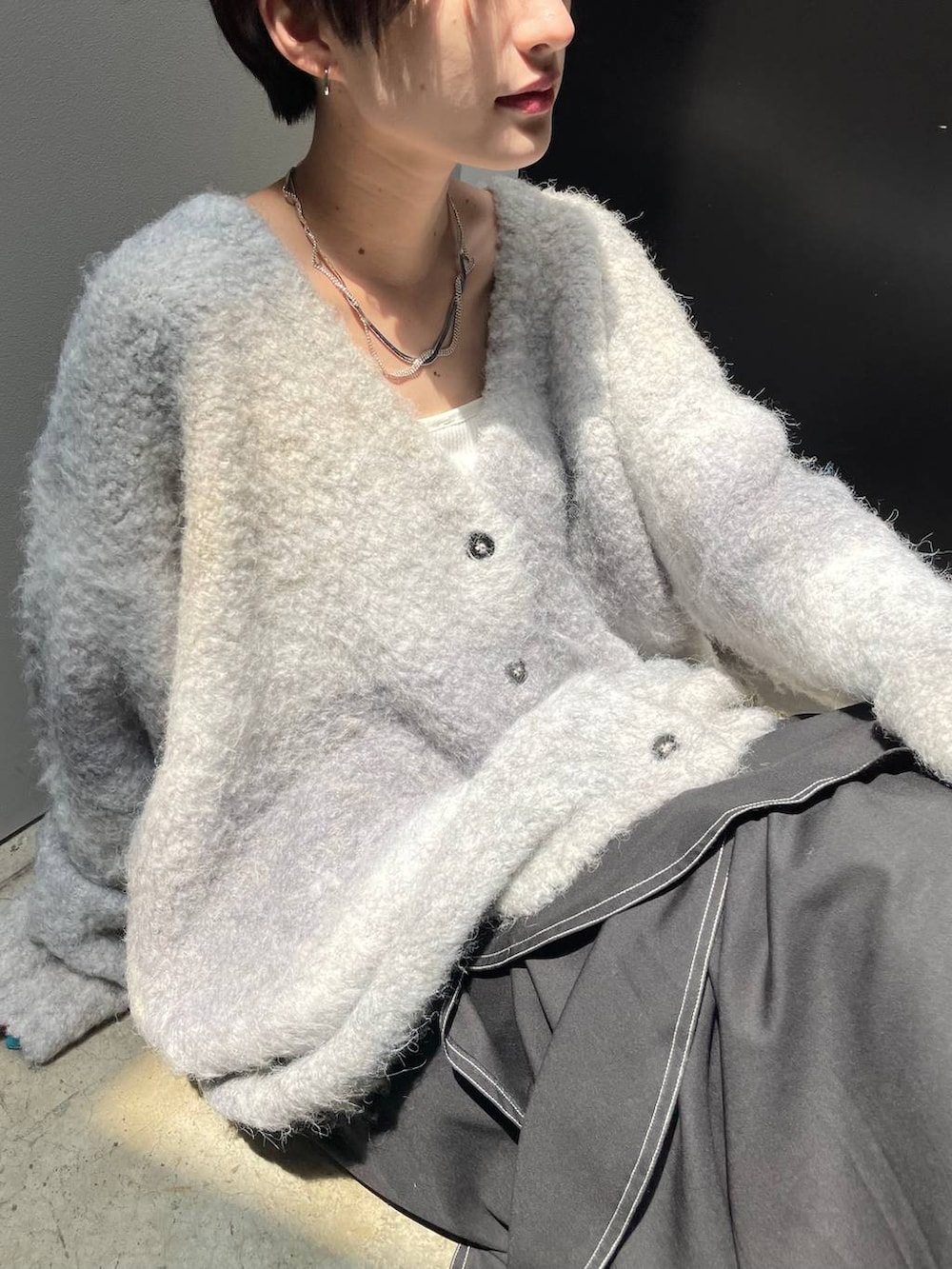 ホワイト系のキャミソール、ブラック系のブーツ、ホワイト系のクラッチバッグを着用したレディースの冬コーディネートの3枚目の写真