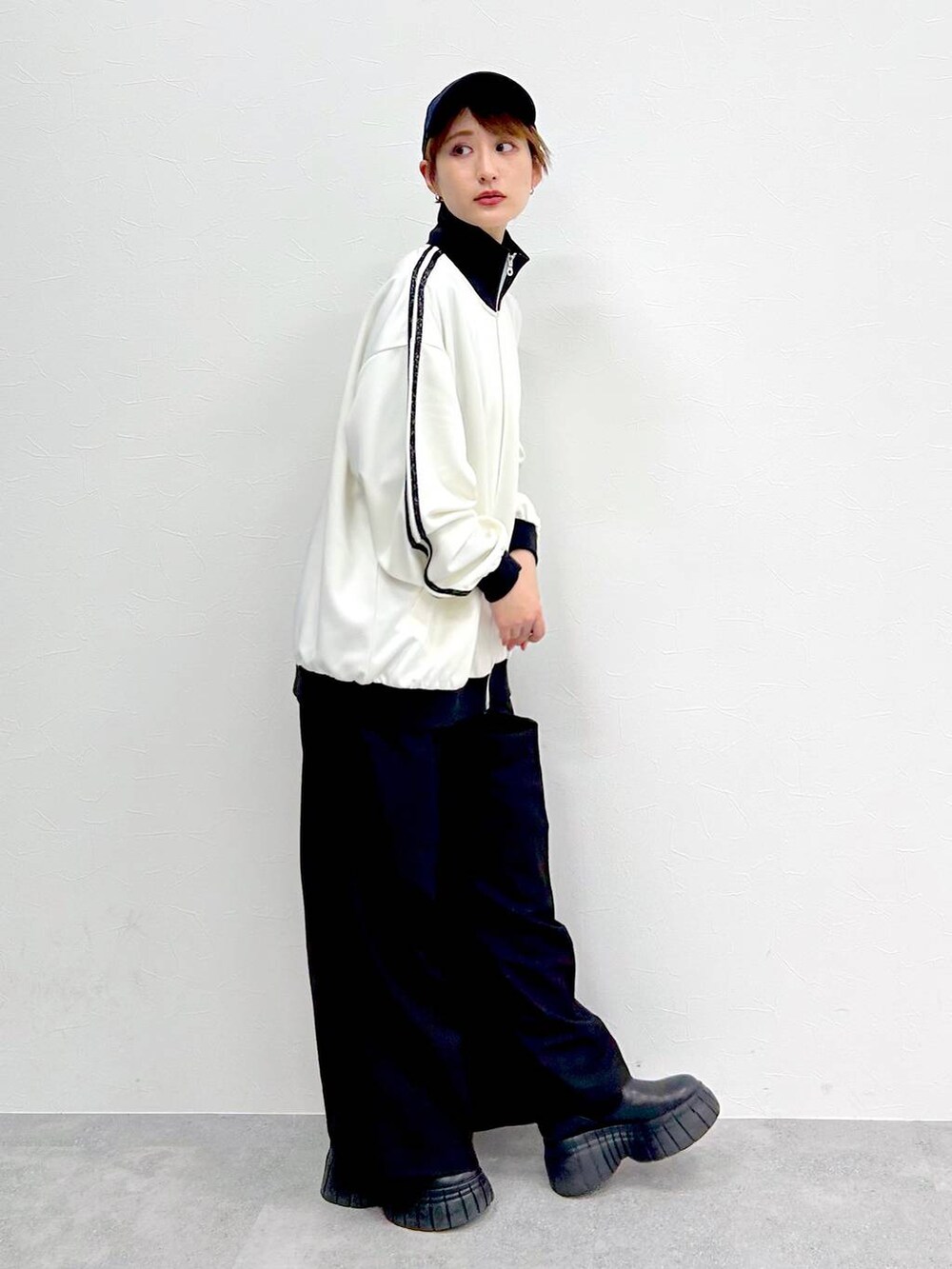 ホワイト系のその他アウター、ブラック系のスラックス、ブラック系のブーツを着用したレディースの春コーディネートの5枚目の写真