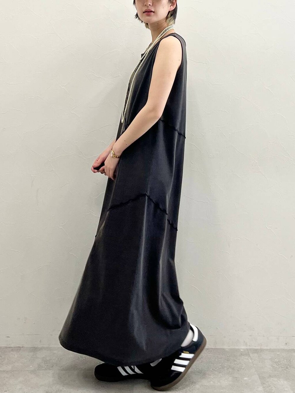 ブラック系のスニーカー、ブラック系のワンピース、ホワイト系のネックレスを着用したレディースの春コーディネートの3枚目の写真