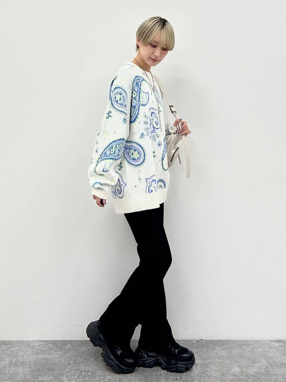 ブラック系のスニーカー、ホワイト系のショルダーバッグ、ブラック系のデニムパンツを着用したレディースの冬コーディネートの5枚目の写真