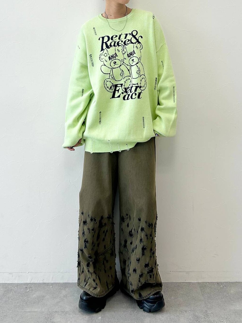 ブラック系のデニムパンツ、ブラック系のブーツ、グリーン系のニット/セーターを着用したレディースの秋コーディネートの2枚目の写真