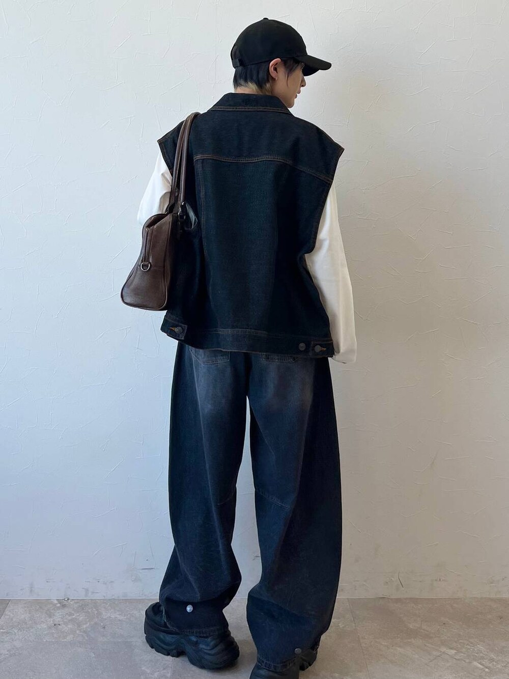 ブラック系のスニーカー、ブラック系のデニムパンツ、ブラウン系のボストンバッグを着用したレディースの春コーディネートの8枚目の写真