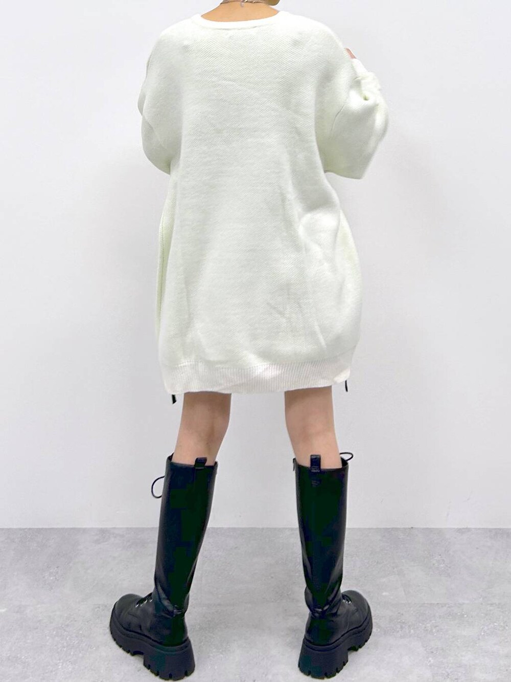 ブラック系のブーツ、ブラック系のスカート、ホワイト系のニット/セーターを着用したレディースの冬コーディネートの6枚目の写真