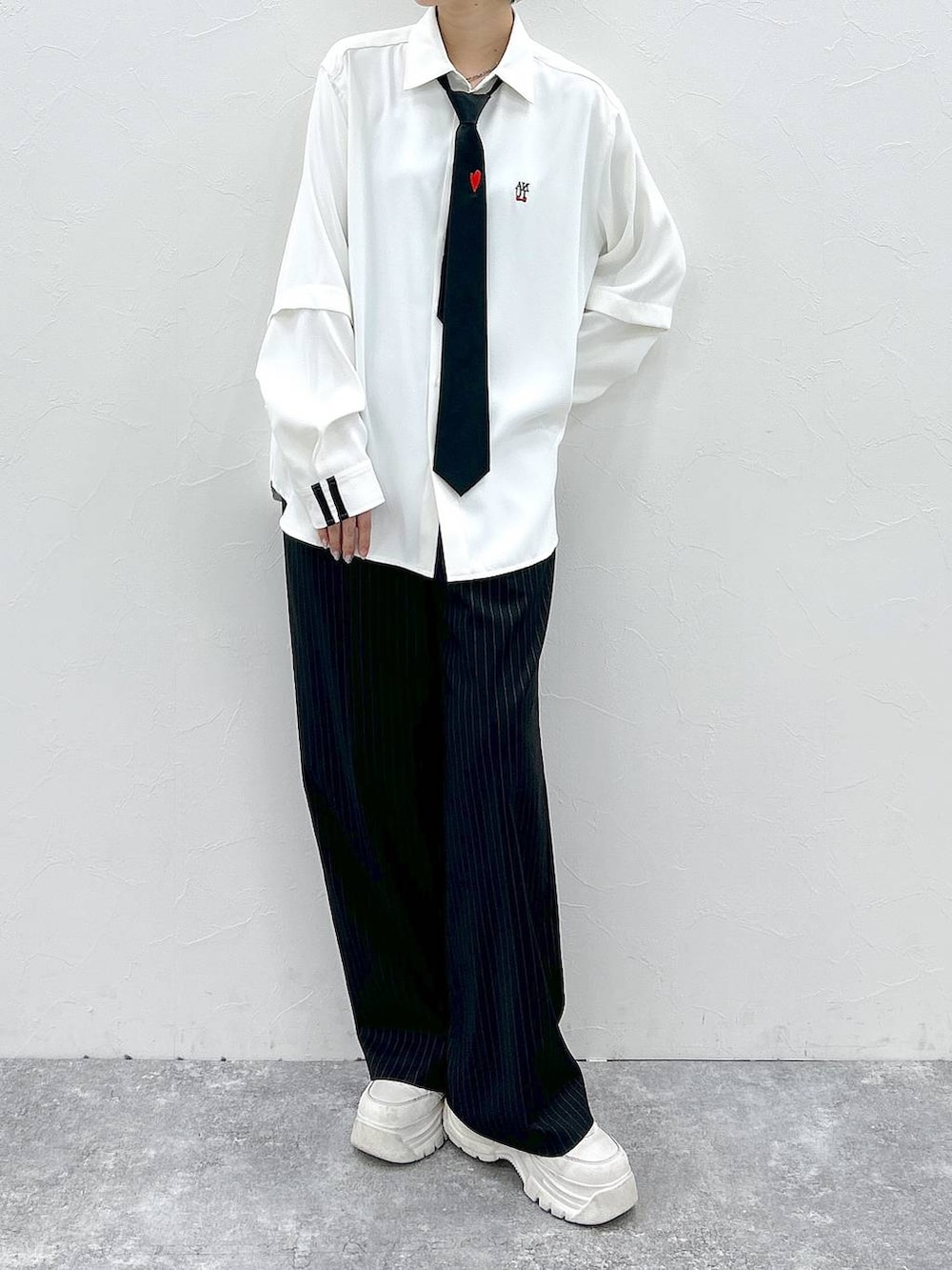 ブラック系のネクタイ、ホワイト系のシャツ/ブラウス、ブラック系のスラックスを着用したレディースの春コーディネートの2枚目の写真