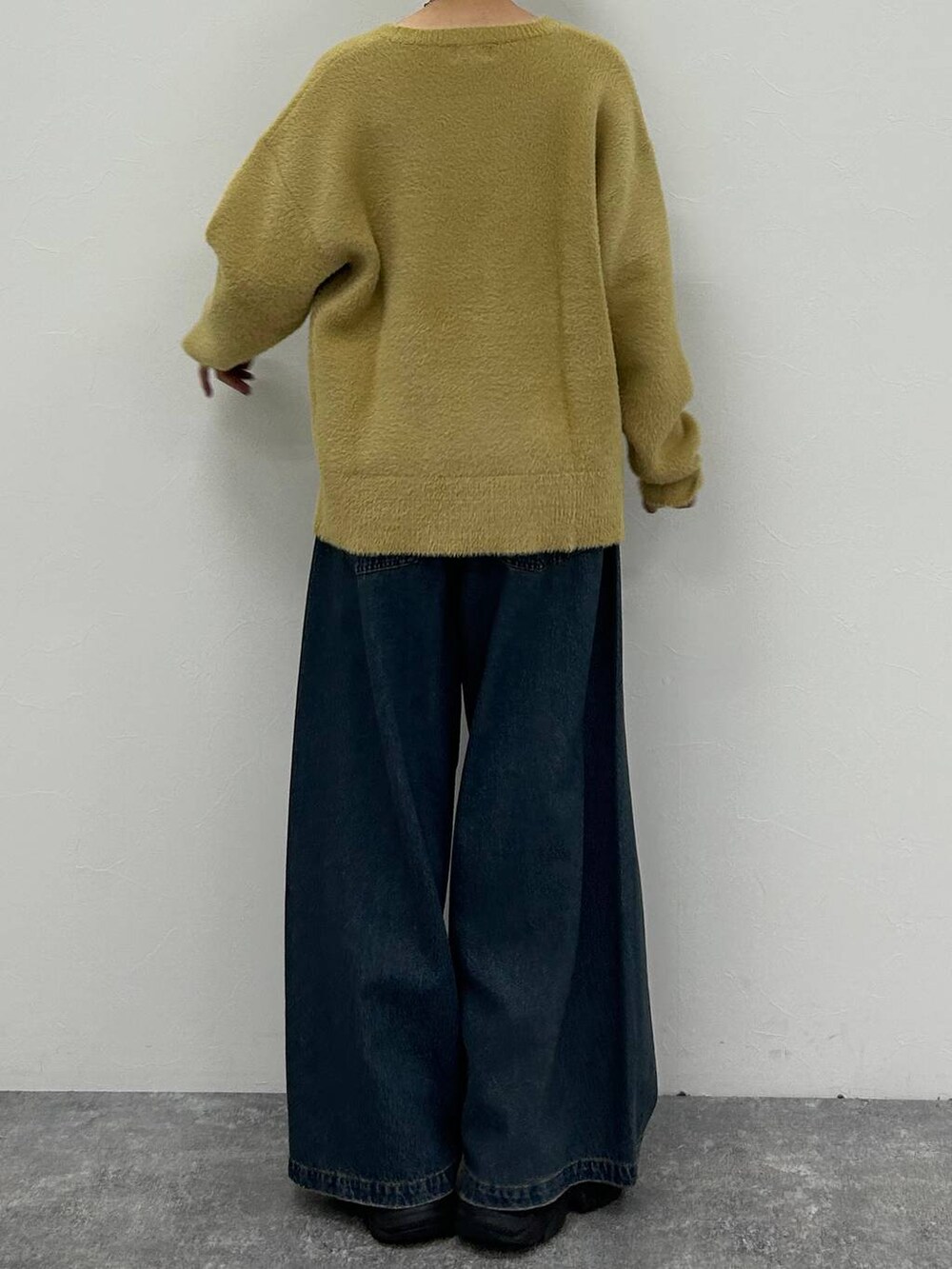 ブラック系のスニーカー、ブルー系のデニムパンツ、イエロー系のニット/セーターを着用したレディースの春コーディネートの9枚目の写真