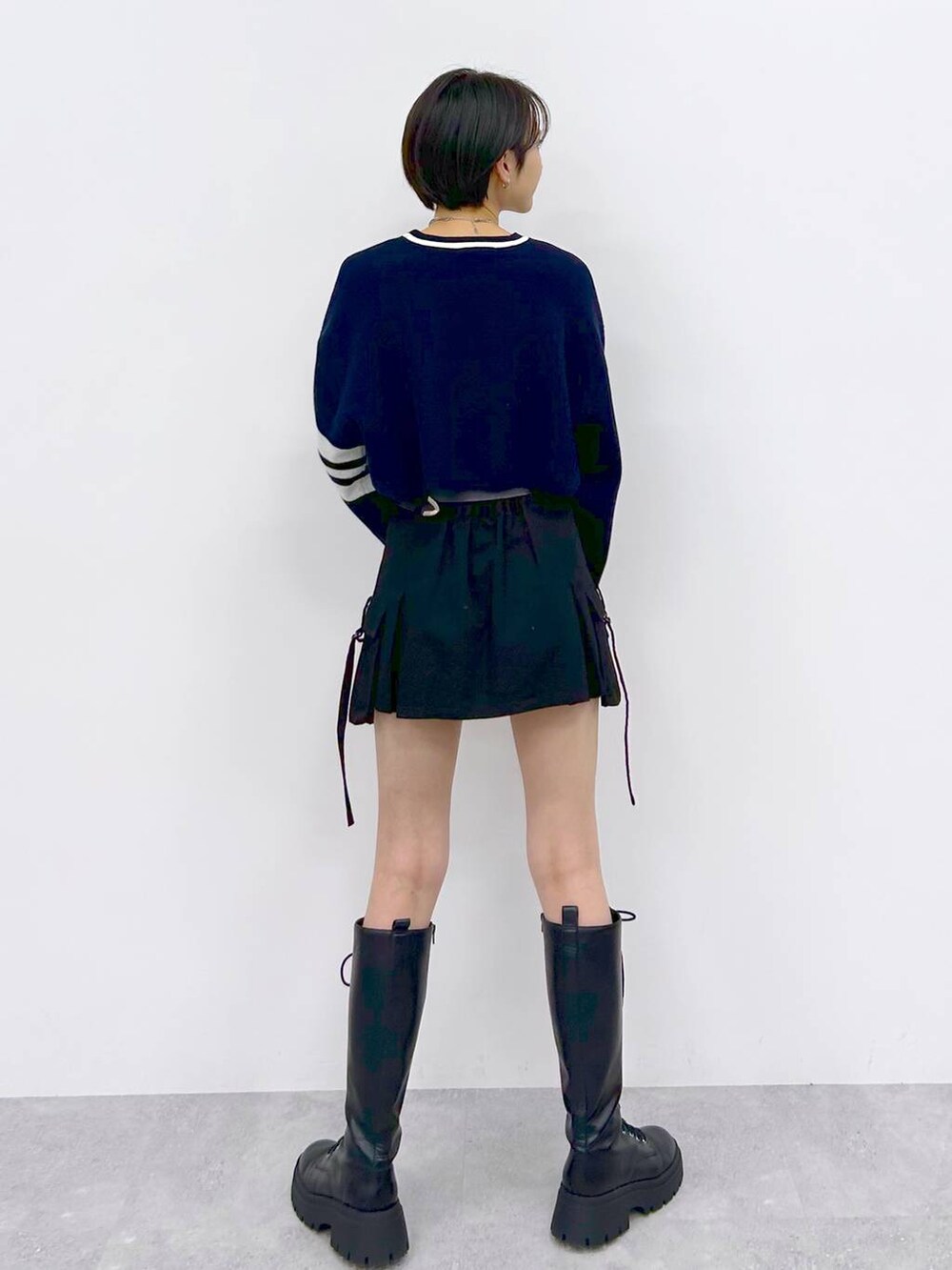 ブラック系のブーツ、ブラック系のスカート、ブルー系のニット/セーターを着用したレディースの冬コーディネートの6枚目の写真