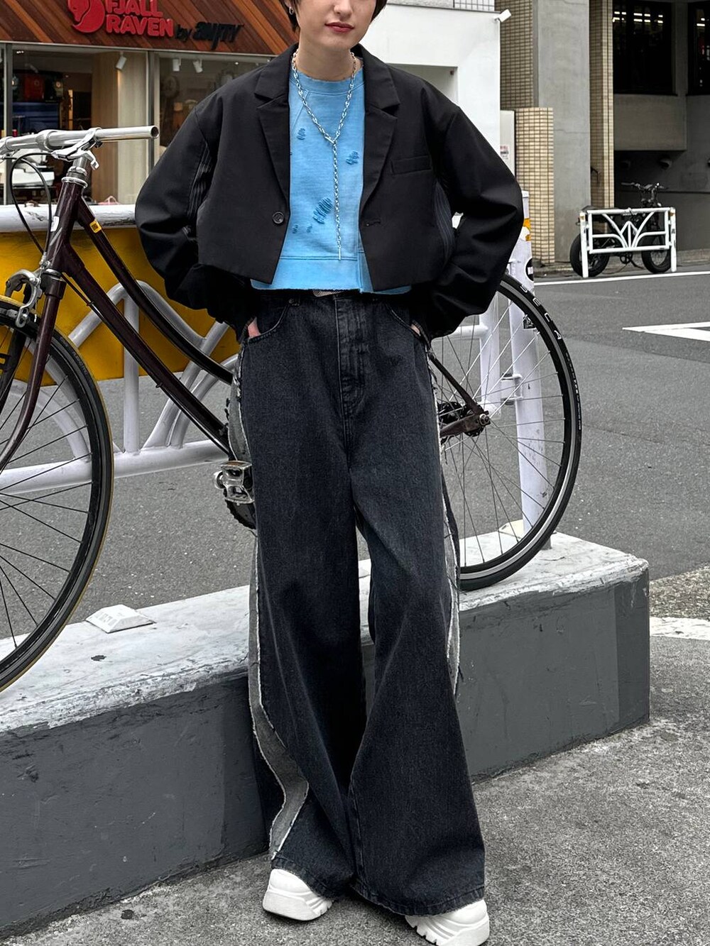 ブラック系のテーラードジャケット、ブラック系のデニムパンツ、ブルー系のスウェットを着用したレディースの春コーディネートの2枚目の写真