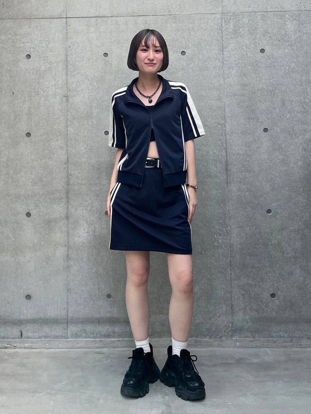 ブラック系のスニーカー、ブラック系のキャミソール、ブルー系のスカートを着用したレディースの夏コーディネートの2枚目の写真