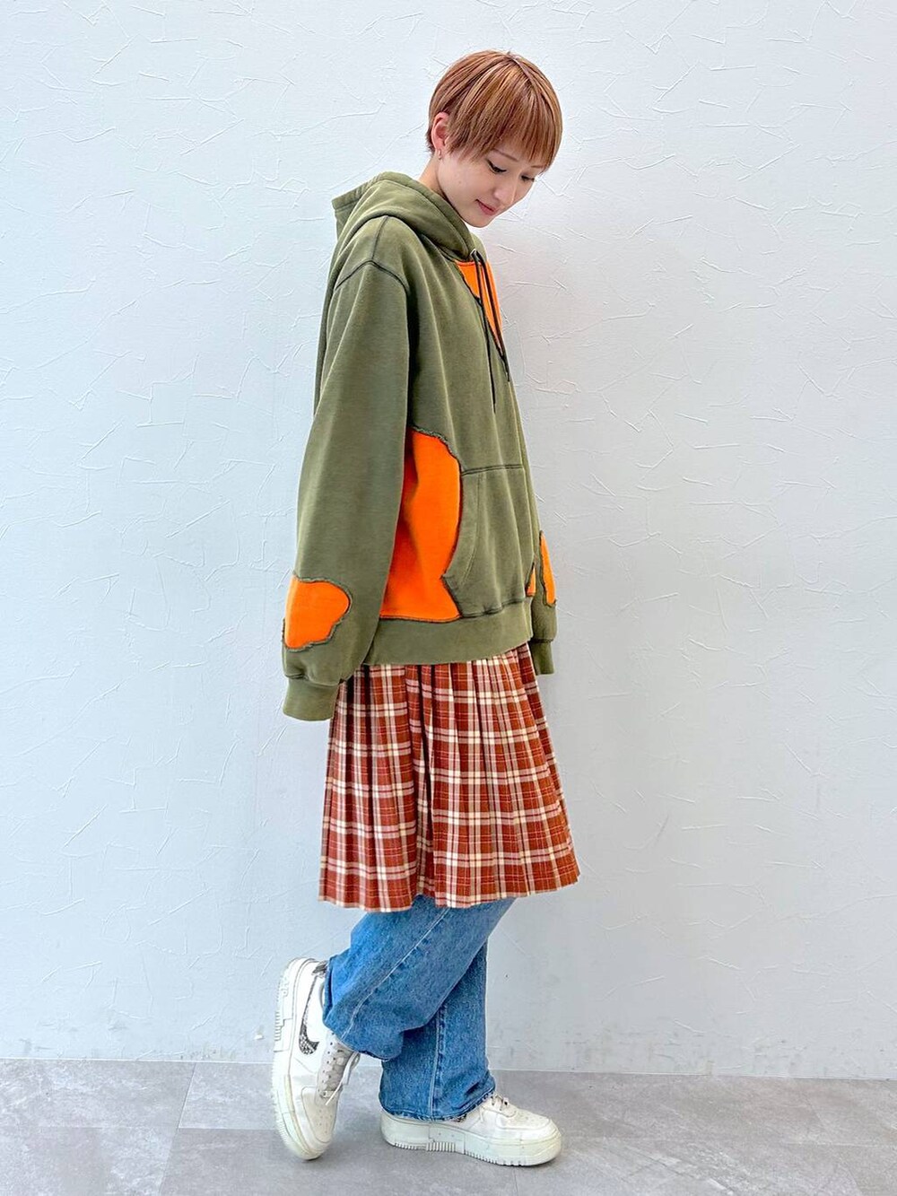 グリーン系のパーカー、レッド系のスカートを着用したレディースの秋コーディネートの4枚目の写真