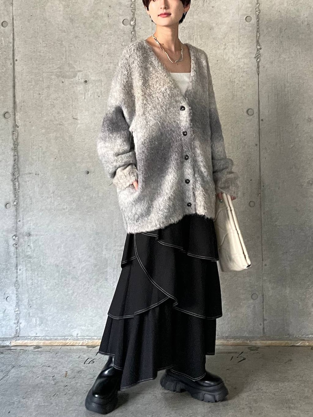 ホワイト系のキャミソール、ブラック系のブーツ、ホワイト系のクラッチバッグを着用したレディースの冬コーディネートの2枚目の写真