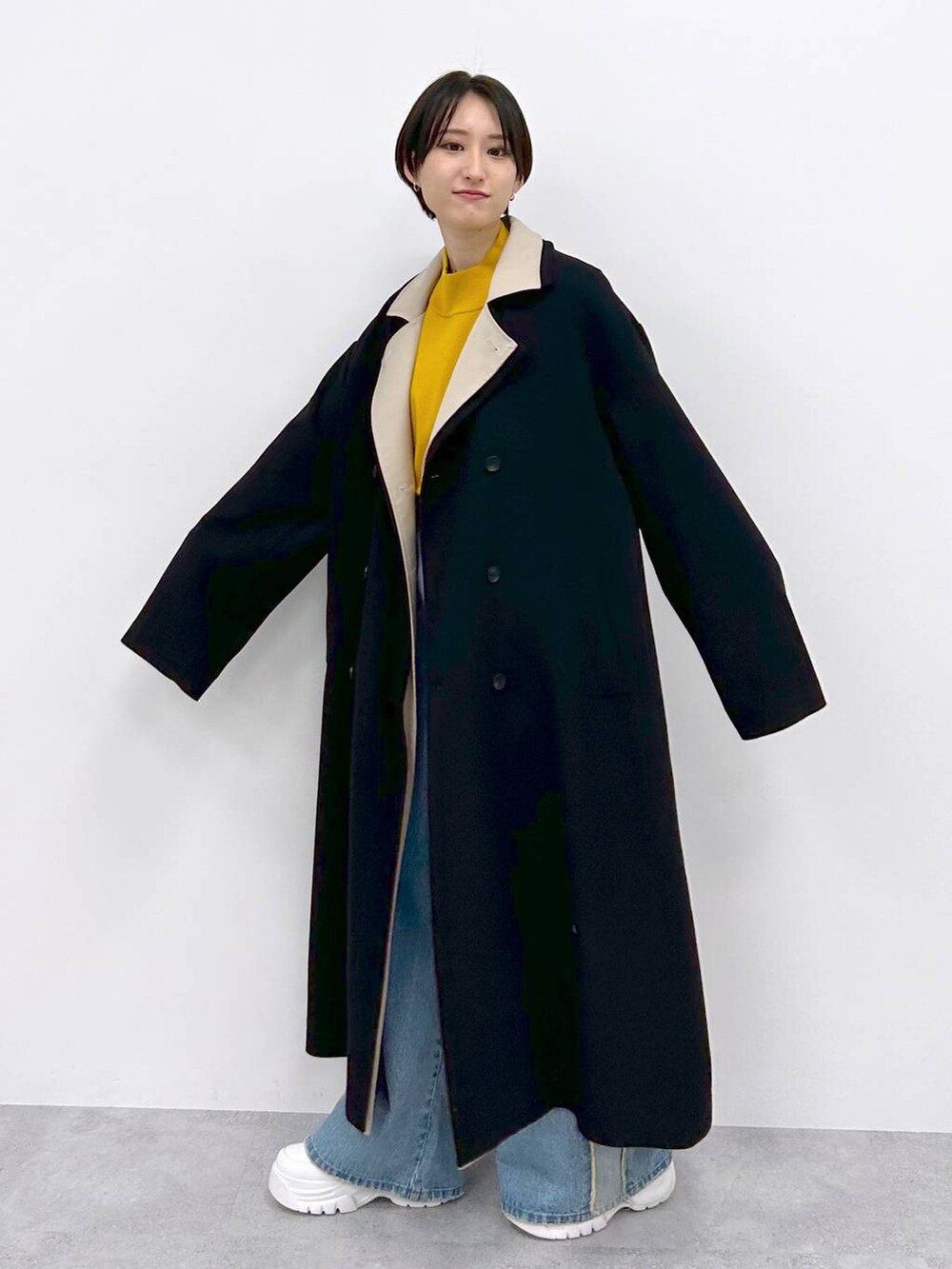 イエロー系のニット/セーター、ブルー系のデニムパンツ、ブラック系のその他アウターを着用したレディースの秋コーディネートの3枚目の写真