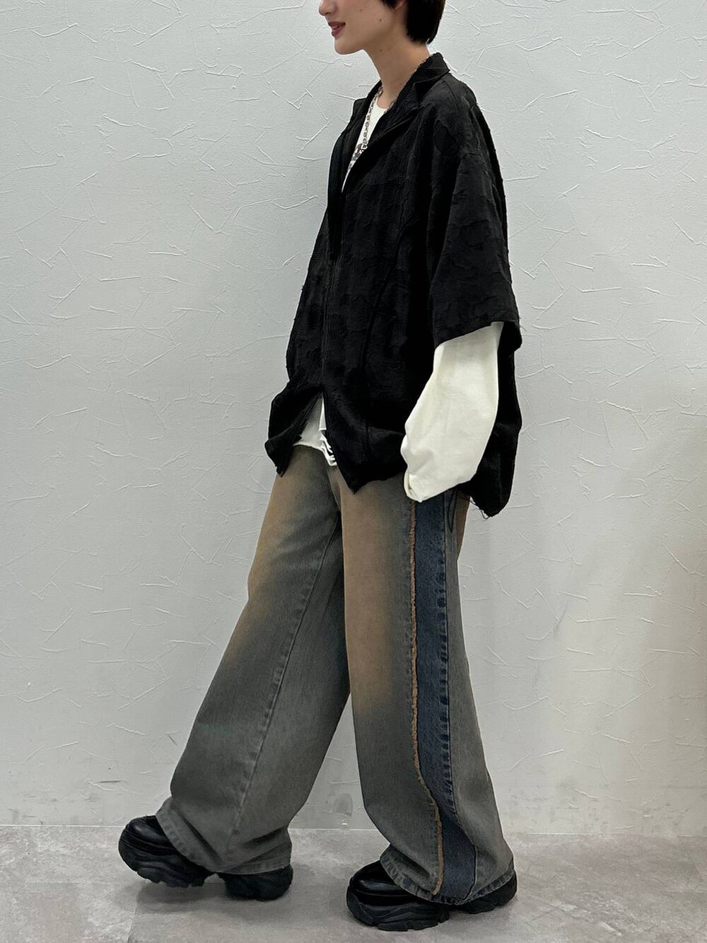 ブラック系のスニーカー、ホワイト系のTシャツ/カットソー、ブルー系のデニムパンツを着用したレディースの秋コーディネートの4枚目の写真