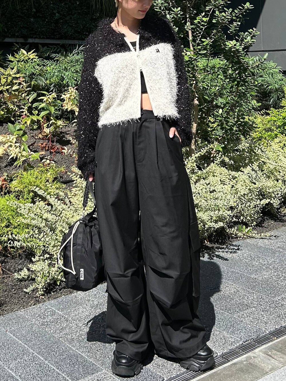 ブラック系のショルダーバッグ、ブラック系のスニーカー、ホワイト系のニット/セーターを着用したレディースの秋コーディネートの2枚目の写真