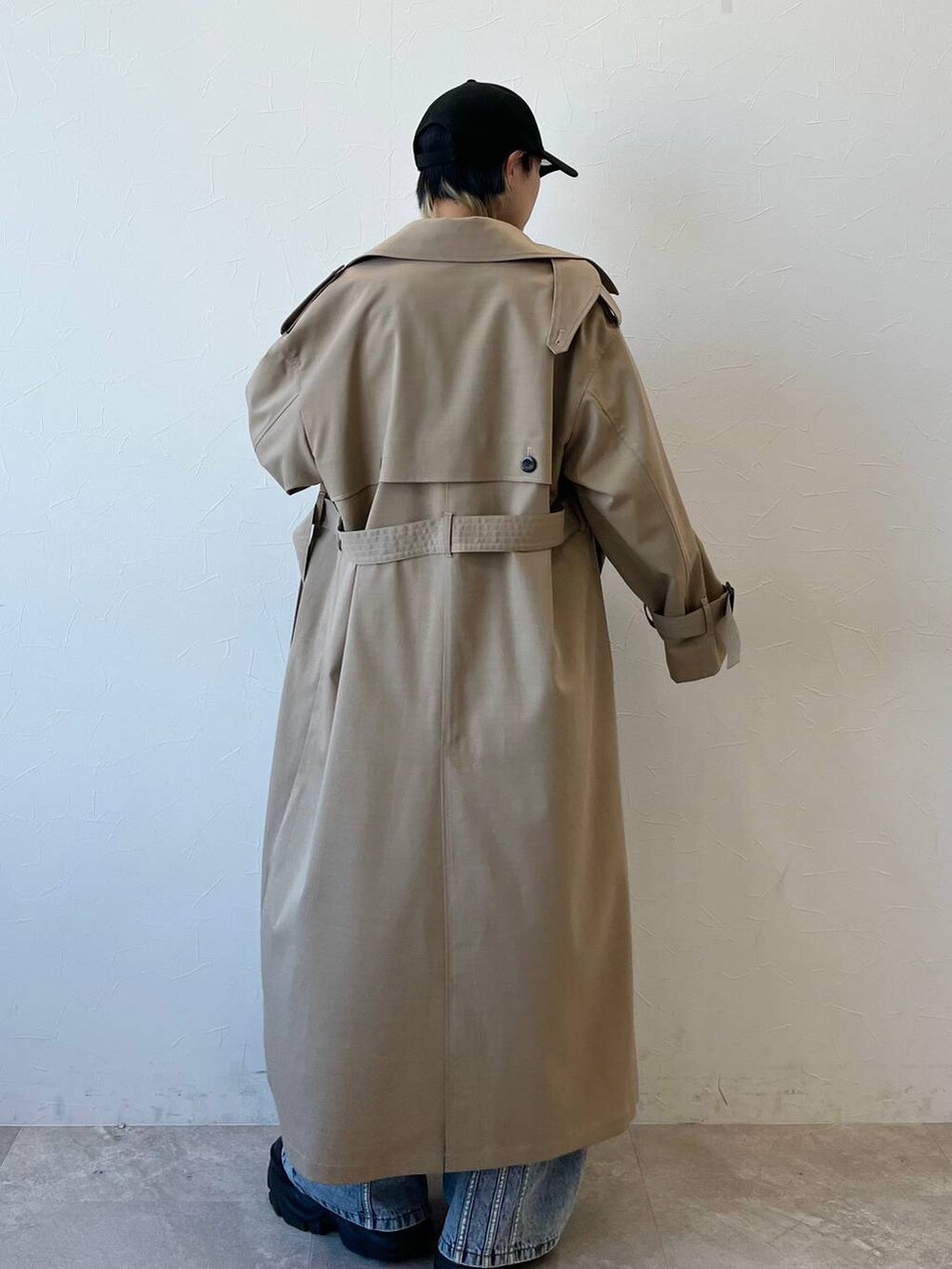 ブラック系のスニーカー、ベージュ系のトレンチコート、ブルー系のデニムパンツを着用したレディースの春コーディネートの6枚目の写真