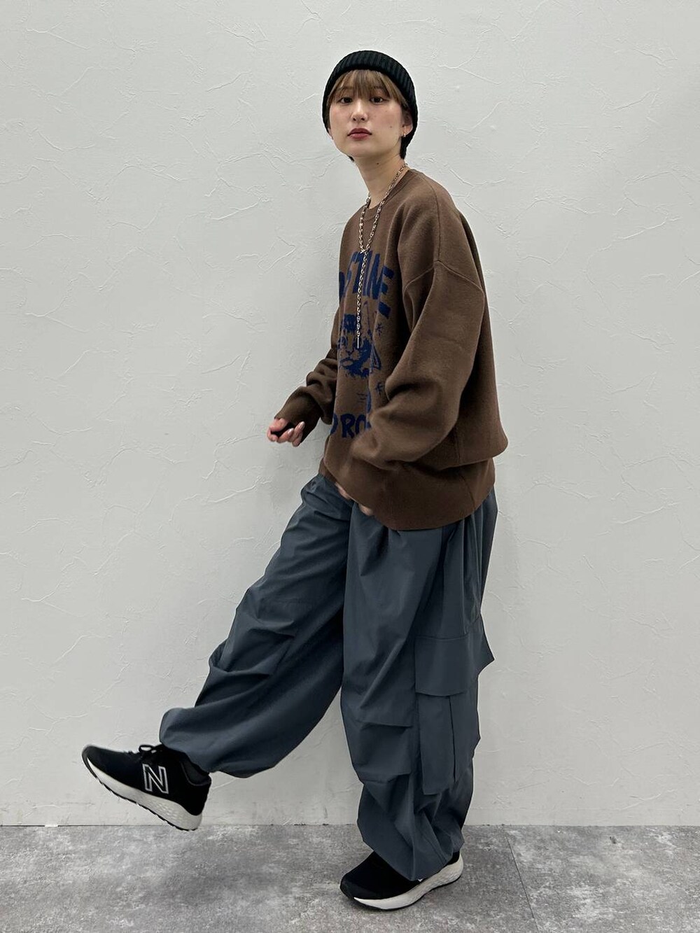 グレー系のカーゴパンツ、ブラウン系のニット/セーター、ブラック系のニットキャップ/ビーニーを着用したレディースの秋コーディネートの3枚目の写真