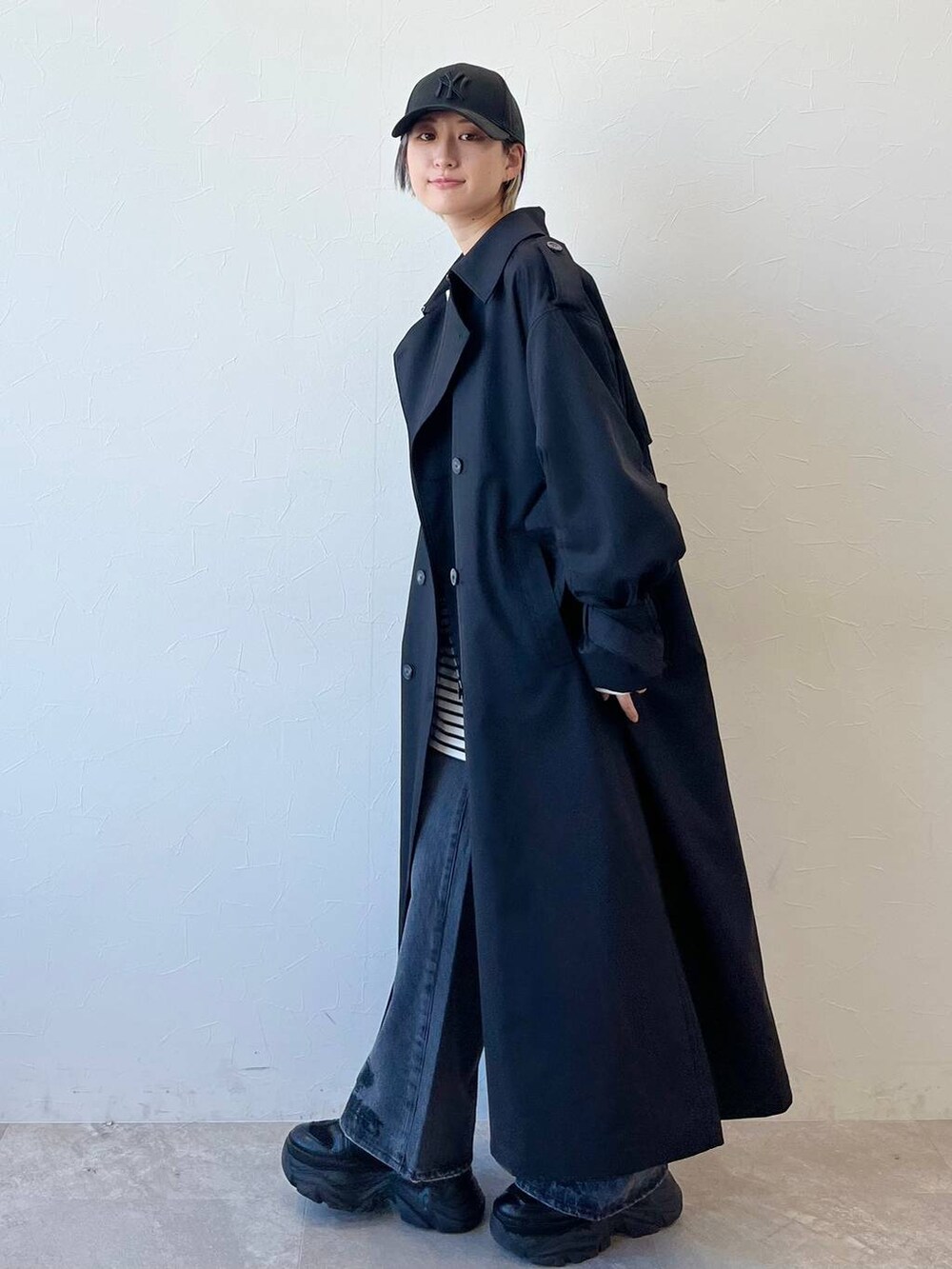 ブラック系のスニーカー、ブラック系のトレンチコート、ブラック系のデニムパンツを着用したレディースの春コーディネートの6枚目の写真