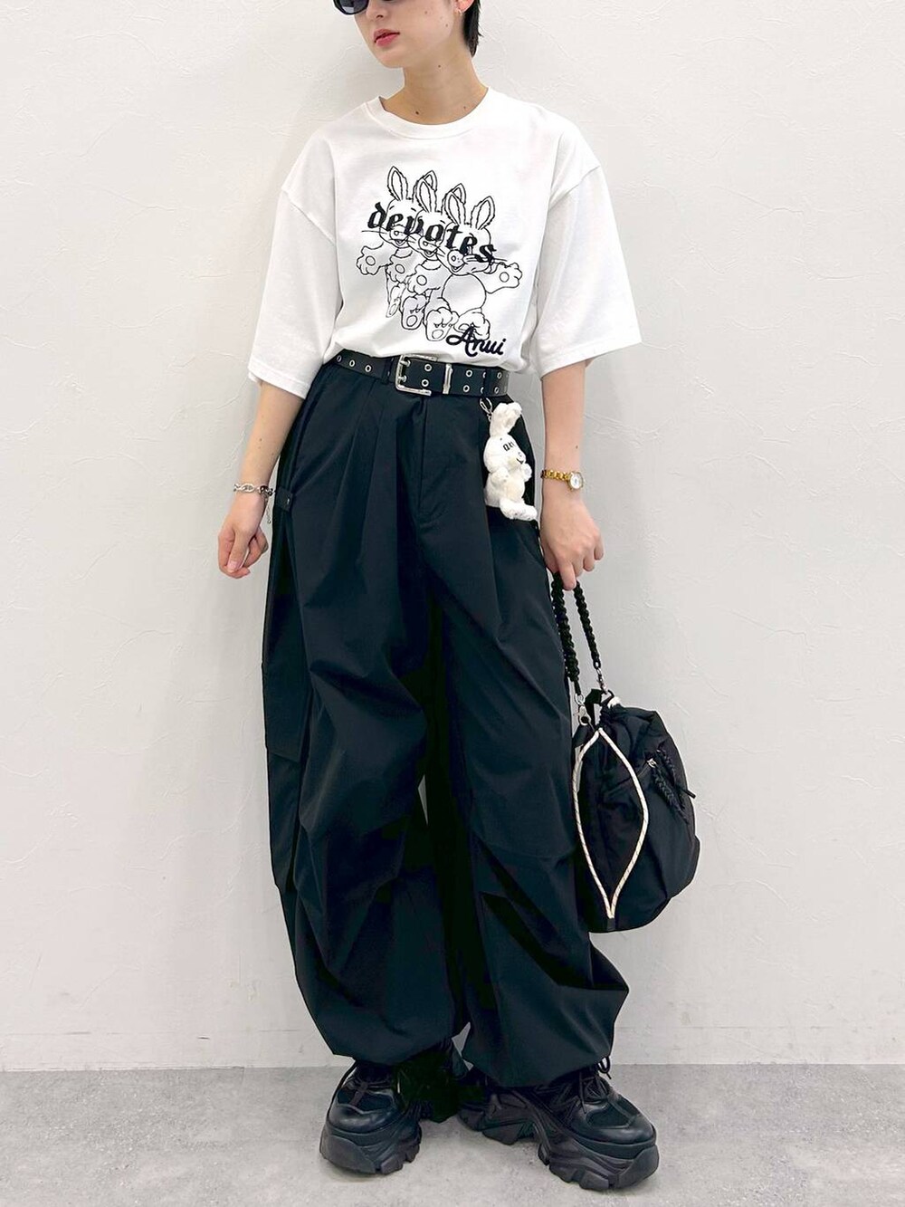 ブラック系のスニーカー、ホワイト系のTシャツ/カットソー、ブラック系のショルダーバッグを着用したレディースの夏コーディネートの3枚目の写真